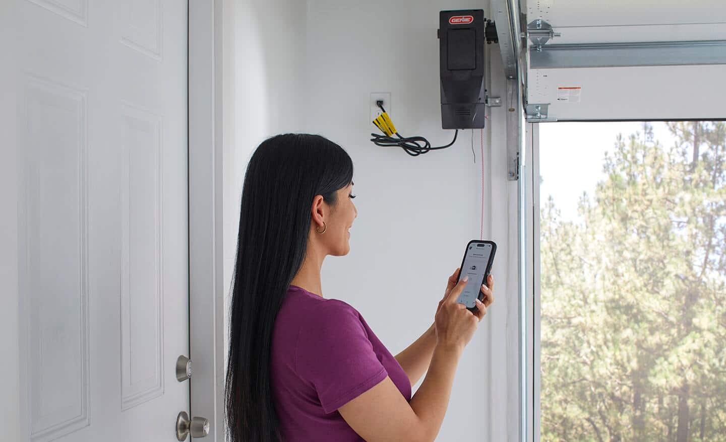Woman using smartphone to control garage door opener