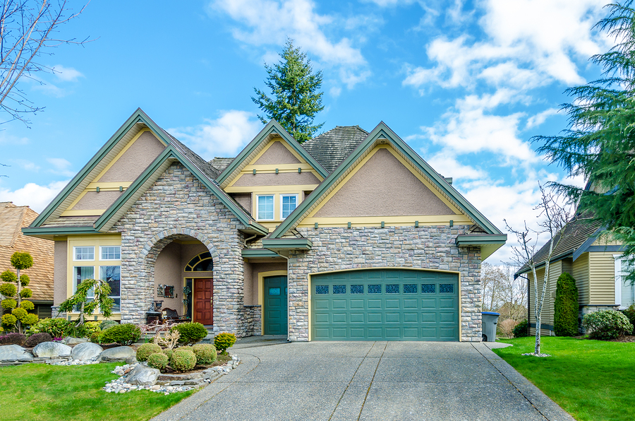 A beautifully designed home features a prominent stone facade, surrounded by well-maintained landscaping and a two-car garage, suggesting a modern aesthetic.
