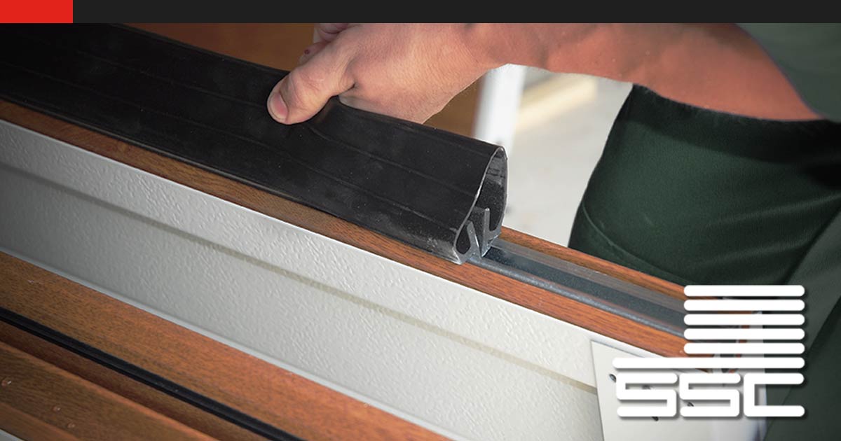 Hand examining garage door weather seal