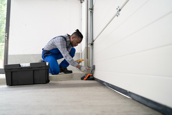 Person examining garage door sensor alignment with level